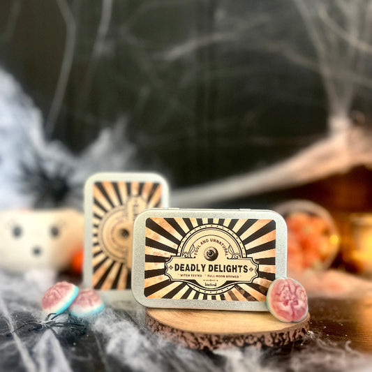 Two tin containers labeled 'Deadly Delights' on a Halloween-themed background with spider webs and pumpkins.